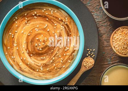 Ein köstliches, wirbelndes Muster aus Tahini-Sauce und Melasse. Traditioneller Tahini und Melasse-Dip aus dem Nahen Osten. Stockfoto