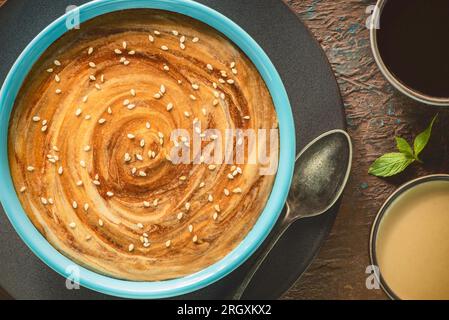 Ein köstliches, wirbelndes Muster aus Tahini-Sauce und Melasse. Traditioneller Tahini und Melasse-Dip aus dem Nahen Osten. Stockfoto