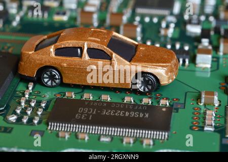 Spielzeugautos auf Elektronikplatine und Mikrochip. Konzeptbild für Halbleiterknappheit, die die Produktion in der Automobilindustrie stört. Stockfoto