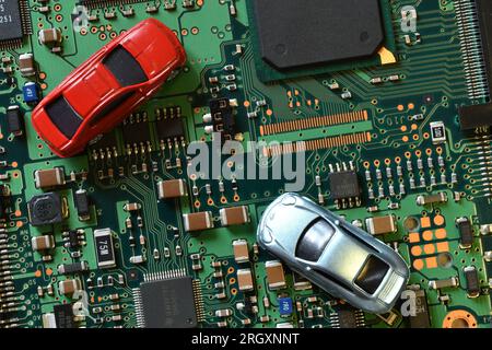 Spielzeugautos auf Elektronikplatine und Mikrochip. Konzeptbild für Halbleiterknappheit, die die Produktion in der Automobilindustrie stört. Stockfoto