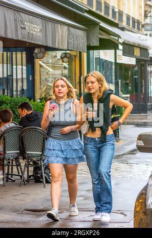 Zwei zwanglos gekleidete Teenager-Mädchen, die auf dem Bürgersteig der Stadt spazieren - Paris 16, Frankreich. Stockfoto