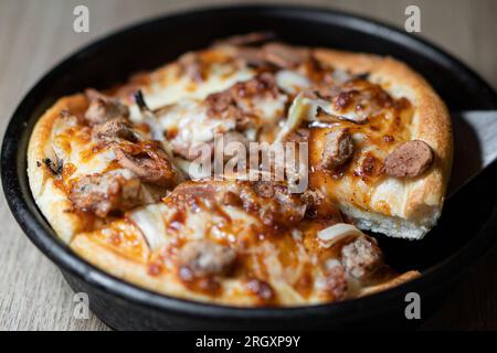 Kleine Mini-Pizza auf Backpapier auf dunklem Holzhintergrund Stockfoto