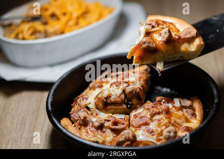 Kleine Mini-Pizza auf Backpapier auf dunklem Holzhintergrund Stockfoto