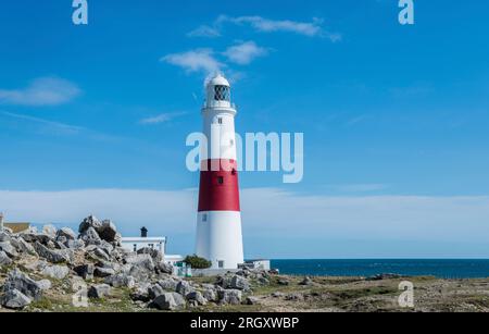 Portland Bill Lighthouse wurde an einem hellen und sonnigen Tag im September mit traditionellem Weiß und Rot und einem strahlend blauen Himmel dahinter fotografiert Stockfoto