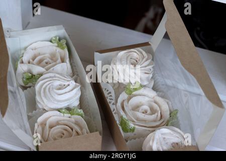 Zephyr-Blumen. Hausgemachte Marshmallows in einer Geschenkbox aus Papier. Die Kiste ist offen. Stockfoto
