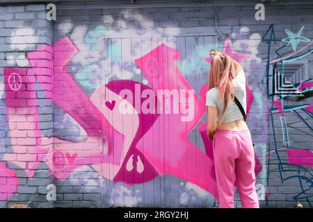 Birmingham, Großbritannien. 12. Aug. 2023. Die Graffiti-Künstlerin „DOLZ“ trägt Barbie Rosa auf ironischere Weise, wenn sie im Digbeth District in Birmingham, Großbritannien, im Rahmen des High Vis Street Art Festivals an verfallenen Wänden arbeitet. Dutzende von Straßengurffiti-Sprays können jedes Jahr in der Stadt ihre Spuren hinterlassen. Kredit: Peter Lopeman/Alamy Live News Stockfoto