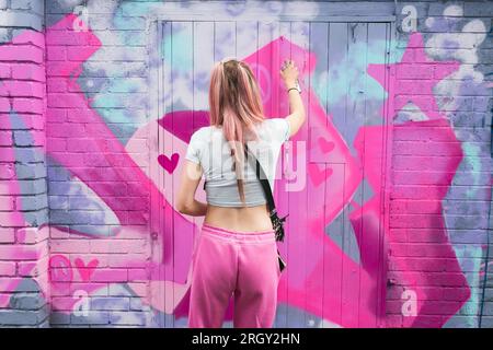 Birmingham, Großbritannien. 12. Aug. 2023. Die Graffiti-Künstlerin „DOLZ“ trägt Barbie Rosa auf ironischere Weise, wenn sie im Digbeth District in Birmingham, Großbritannien, im Rahmen des High Vis Street Art Festivals an verfallenen Wänden arbeitet. Dutzende von Straßengurffiti-Sprays können jedes Jahr in der Stadt ihre Spuren hinterlassen. Kredit: Peter Lopeman/Alamy Live News Stockfoto