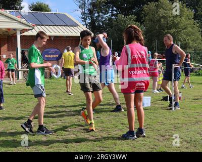 Kesgrave, Suffolk - 12. August 2023 : Kesgrave's 400. Park Run Event auf dem Millennium Field. Die Jungs an der Ziellinie halten ihre Timer an. Stockfoto