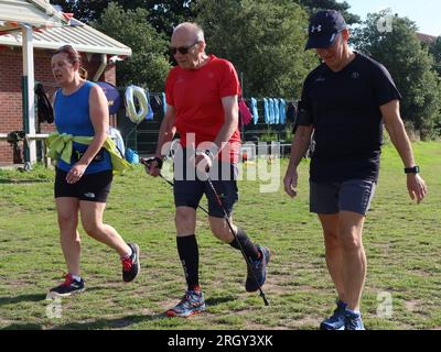 Kesgrave, Suffolk - 12. August 2023 : Kesgrave's 400. Park Run Event auf dem Millennium Field. Ein älterer Nordic, der auf dem Platz mit Stöcken herumläuft. Stockfoto