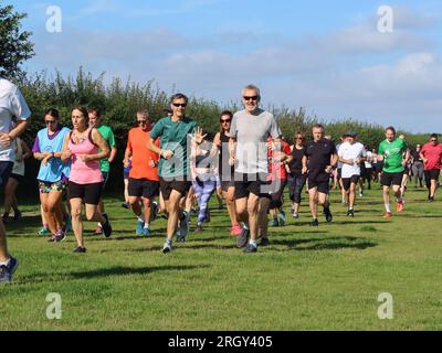 Kesgrave, Suffolk - 12. August 2023 : Kesgrave's 400. Park Run Event auf dem Millennium Field. Lächelnde Läufer genießen die Veranstaltung. Stockfoto