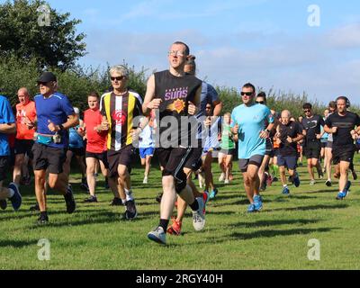 Kesgrave, Suffolk - 12. August 2023 : Kesgrave's 400. Park Run Event auf dem Millennium Field. Gruppe von Läufern jeden Alters. Stockfoto