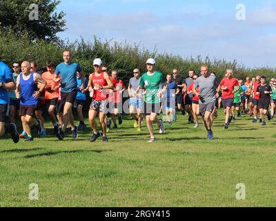 Kesgrave, Suffolk - 12. August 2023 : Kesgrave's 400. Park Run Event auf dem Millennium Field. Gruppe von Läufern jeden Alters. Stockfoto