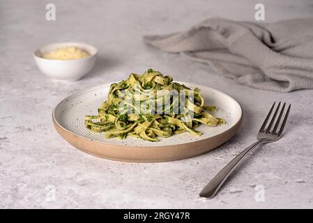 Lebensmittelfotografie von Teigwaren; Tagliatelle, Fettuccine; Trenette; Spinat; Oregano; Parmesan; Käse; Soße, Oliven; Hartweizen, Grieß, Grieß, Gabel bac Stockfoto