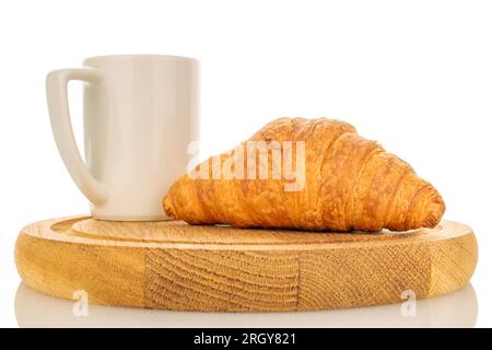 Ein frisch gebackenes duftendes Croissant auf einem Holztablett mit einer weißen Tasse, aus der Nähe, isoliert auf Weiß. Stockfoto
