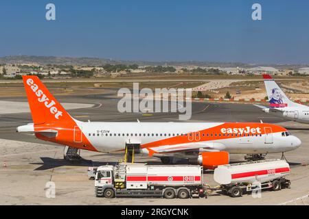 Luqa, Malta - 7. August 2023: Urlaubsjet Airbus A320 am Boden des Internationalen Flughafens Malta mit Tankschiff daneben Stockfoto