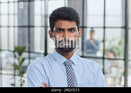 Nahaufnahme eines jungen, attraktiven, ernsthaften Kerls in blauem Hemd, der direkt in die Kamera schaut Stockfoto