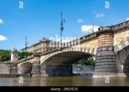 „Most Legií“ (Legionsbrücke) über der Moldau in Prag. Granitbögen mit Lampen und ehemalige Mautstelle auf der linken Uferseite der Brücke. Stockfoto