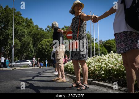 Madrid, Spanien. 12. Aug. 2023. Eine Gruppe von Aktivisten bildet während der Kundgebung eine menschliche Kette um den Neptun-Brunnen. Fast hundert Menschen haben sich am Neptun-Brunnen in Madrid unter dem Slogan "Hug the Mar Menor" versammelt, um eine menschliche Kette zu schaffen mit dem Ziel, die "Grenzsituation" zu verteidigen, die das Maditerraneo erlebt. Kredit: SOPA Images Limited/Alamy Live News Stockfoto