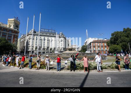 Madrid, Spanien. 12. Aug. 2023. Eine Gruppe von Aktivisten bildet während der Kundgebung eine menschliche Kette um den Neptun-Brunnen. Fast hundert Menschen haben sich am Neptun-Brunnen in Madrid unter dem Slogan "Hug the Mar Menor" versammelt, um eine menschliche Kette zu schaffen mit dem Ziel, die "Grenzsituation" zu verteidigen, die das Maditerraneo erlebt. Kredit: SOPA Images Limited/Alamy Live News Stockfoto