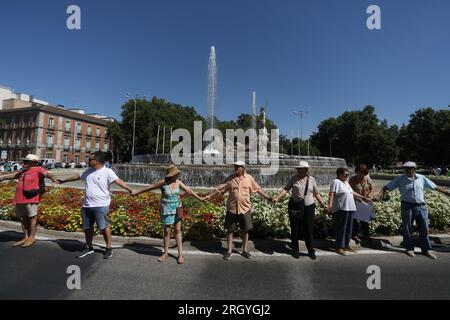 Madrid, Spanien. 12. Aug. 2023. Eine Gruppe von Aktivisten bildet während der Kundgebung eine menschliche Kette um den Neptun-Brunnen. Fast hundert Menschen haben sich am Neptun-Brunnen in Madrid unter dem Slogan "Hug the Mar Menor" versammelt, um eine menschliche Kette zu schaffen mit dem Ziel, die "Grenzsituation" zu verteidigen, die das Maditerraneo erlebt. Kredit: SOPA Images Limited/Alamy Live News Stockfoto