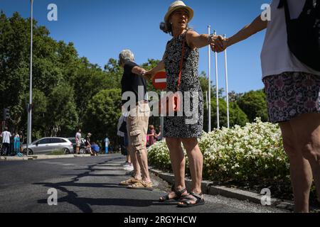 Madrid, Spanien. 12. Aug. 2023. Eine Gruppe von Aktivisten bildet während der Kundgebung eine menschliche Kette um den Neptun-Brunnen. Fast hundert Menschen haben sich am Neptun-Brunnen in Madrid unter dem Slogan "Hug the Mar Menor" versammelt, um eine menschliche Kette zu schaffen mit dem Ziel, die "Grenzsituation" zu verteidigen, die das Maditerraneo erlebt. (Foto: David Canales/SOPA Images/Sipa USA) Guthaben: SIPA USA/Alamy Live News Stockfoto