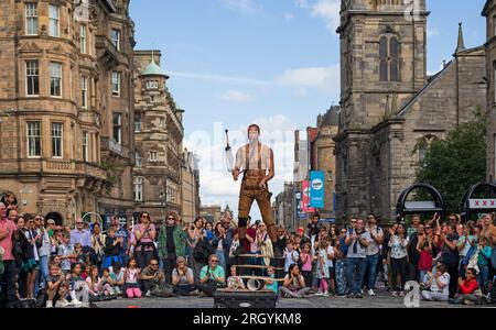 Royal Mile, Edinburgh, Schottland, Großbritannien. 12. August 2023. Edinburgh Festival Fringe, Straßenkünstler in der High Street, die ein großes Publikum aufführen, windig für Jongleure auf Plattformen, Sonnenschein und gelegentlich heftige Duschen. Pictured Reidiculous jongliert mit verschiedenen Instrumenten, die auf seiner Plattform in der windigen High Street stehen. Kredit: Archwhite/alamy Live News. Stockfoto