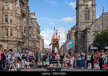 Royal Mile, Edinburgh, Schottland, Großbritannien. 12. August 2023. Edinburgh Festival Fringe, Straßenkünstler in der High Street, die ein großes Publikum aufführen, windig für Jongleure auf Plattformen, Sonnenschein und gelegentlich heftige Duschen. Pictured Reidiculous jongliert mit verschiedenen Instrumenten, die auf seiner Plattform in der windigen High Street stehen. Kredit: Archwhite/alamy Live News. Stockfoto