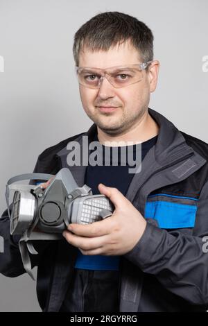 Ein Mann hält eine Atemschutzmaske zum Schutz vor Staub und Gasen. Stockfoto