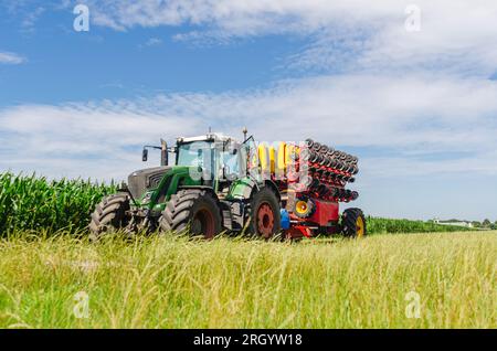 Sämaschine im grünen Maisfeld. Ansicht aus niedrigem Winkel. Helle Landschaftsgestaltung mit Maschinen Stockfoto