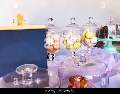 Flohmarkt, Makkaroni, Kuchen und Donuts auf dem Tisch, Werbemodell mit Holzkreidetafel Stockfoto