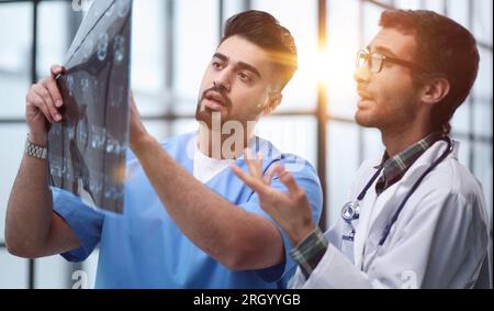 Ärzte und ein Praktikant untersuchen eine Röntgenaufnahme eines Patienten. MRT-Scans von Hirnaktivität und Wissenschaftlern. Stockfoto