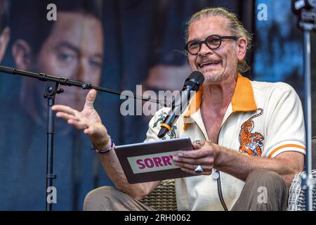 Cottbus, Deutschland. 12. Aug. 2023. Schauspieler Götz Otto sitzt auf einer Bühne des Elbenwald Festivals für eine Live-Episode des Radioauftritts Kohlrabenschwarz. Das Elbenwald Festival ist ein dreitägiges Treffen für Menschen jeden Alters, die Filme, Fantasie, Spiele, Konzerte und eine beliebige Kombination der oben genannten genießen. Die Organisatoren erwarten etwa 15.000 Besucher. Kredit: Frank Hammerschmidt/dpa/Alamy Live News Stockfoto