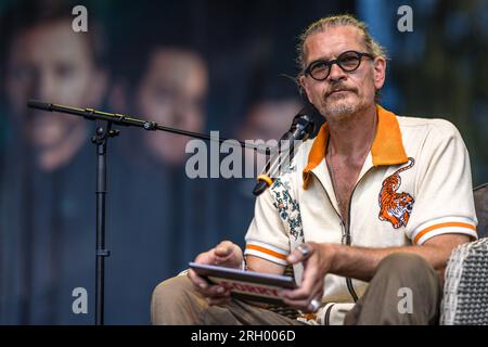 Cottbus, Deutschland. 12. Aug. 2023. Schauspieler Götz Otto sitzt auf einer Bühne des Elbenwald Festivals für eine Live-Episode des Radioauftritts Kohlrabenschwarz. Das Elbenwald Festival ist ein dreitägiges Treffen für Menschen jeden Alters, die Filme, Fantasie, Spiele, Konzerte und eine beliebige Kombination der oben genannten genießen. Die Organisatoren erwarten etwa 15.000 Besucher. Kredit: Frank Hammerschmidt/dpa/Alamy Live News Stockfoto