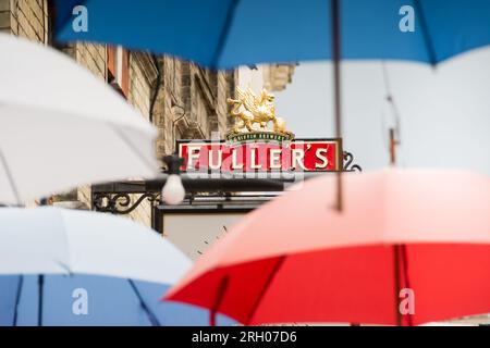 Nahaufnahme des Fuller's Griffin Brewery Pub Schilds inmitten farbenfroher roter, weißer und blauer Regenschirme am Church Court, Richmond, England, Surrey, Großbritannien Stockfoto