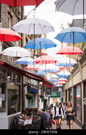 Junge Frauen laufen unter farbenfrohen roten, weißen und blauen Schirmen am Church Court, Richmond, TW9, Surrey, England, GROSSBRITANNIEN Stockfoto