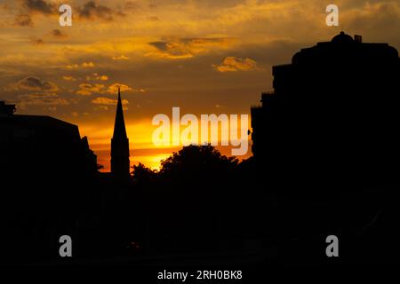 Silhouetten historischer Gebäude vor einem orangefarbenen Himmel in der Dämmerung in Oradea, Rumänien Stockfoto