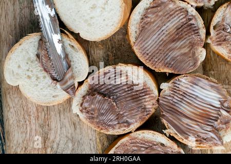 Frisches, weiches Baguette in Stücke schneiden und mit Schokoladencreme, Schokoladenpaste auf einem weißen Weizenbaguette verteilen Stockfoto