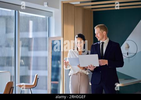 Zwei vielbeschäftigte Kollegen, die über das Projekt „Walking in Office“ sprechen. Stockfoto