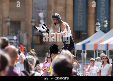 Straßenkünstler unterhalten die Menge beim Edinburgh Fringe Festival im The Mound in Edinburgh, Schottland, Großbritannien Stockfoto