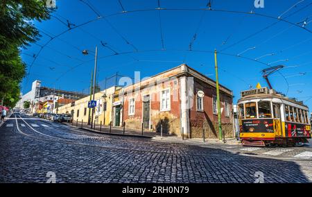 Lissabon, Portugal. Straßenszene mit Straßenbahn in Calcada da Ajuda. Die moderne Fassade des Palacio National de Ajuda im Hintergrund. Stockfoto