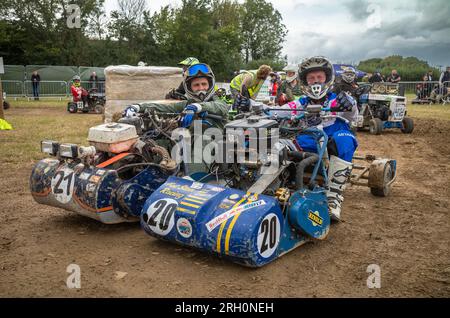 Die Fahrer sitzen auf ihren Rasenmähern und warten darauf, den BLMRA 500 zu starten, ein 500-km-Rennen im Le Mans-Stil über Nacht auf einem Feld in West Sussex, Großbritannien. Die British Lawn Mower Racing Association veranstaltet samstags/sonntags ihr 50.-jähriges 12-stündiges Rennen mit 52 Teams, jeweils mit drei Fahrern. Stockfoto