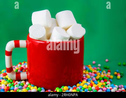 Rote Schüssel mit Marshmallows über farbigen Kugeln Stockfoto