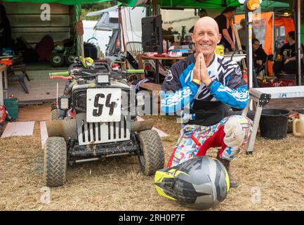 Leon Clark, Fahrer eines Rasenmähers, kniet neben seinem Rasenmäher, um für Erfolg zu beten, bevor der BLMRA 500, ein 500 km langer Rasenmäher im Le Mans-Stil über Nacht auf einem Feld in West Sussex, Großbritannien, stattfindet. Die British Lawn Mower Racing Association veranstaltet samstags/sonntags ihr 50.-jähriges 12-stündiges Rennen mit 52 Teams, von denen jedes bis zu drei Fahrer hat. Stockfoto