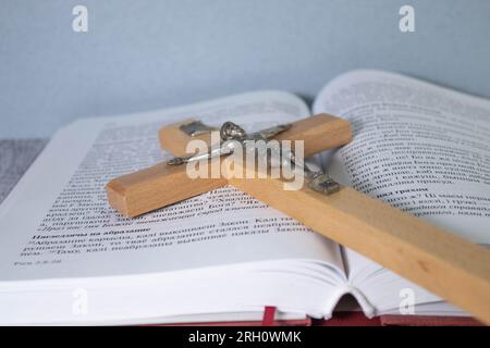 Holzkreuz, Heilige Bibel und weiße Lilie auf dem Tisch. Stockfoto