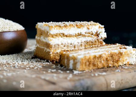 Cremige Sahne und Karamellkuchen mit Sesamsamen während der Dessertzubereitung, mehrlagiger Kuchen mit Sesamsamen Stockfoto