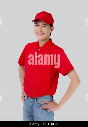 Porträtieren Sie einen jungen asiatischen Mann in Uniform, stehen Sie und lächeln Sie mit einem selbstbewussten, isolierten weißen Hintergrund, Mitarbeiter oder Händler, Kurier und Zusteller, Zusteller Stockfoto