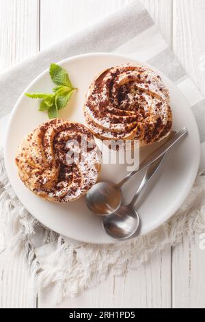 Französisches Dessert paris-brest mit Puderzucker und Kakao auf einem Teller auf dem Holztisch. Vertikale Draufsicht von oben Stockfoto