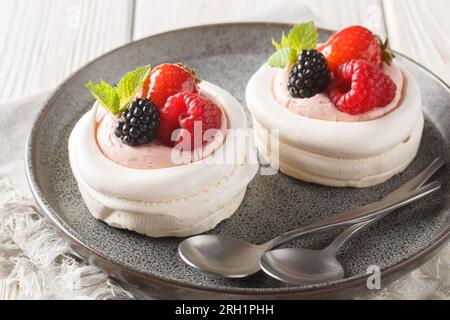 Anna Pavlova Baiser-Kuchen mit Sahne und frischen Sommerbeeren auf einem Teller auf dem Holztisch. Horizontal Stockfoto