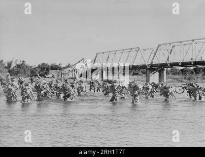 Malaya Campaign, Dezember 1941 – Februar 1942. Da es keinen solchen Luxus gibt, wertvolle Zeit zu verschwenden und darauf zu warten, dass ihre Ingenieure eine weitere gestürzte Brücke reparieren, waten die „Ginrin Butai“ (silbernes Radsportkorps) der kaiserlichen Japanischen Armee über einen Fluss, während sie ihre unerschütterliche Fahrt nach Singapur, etwa im Februar 1942, fortsetzten. Stockfoto