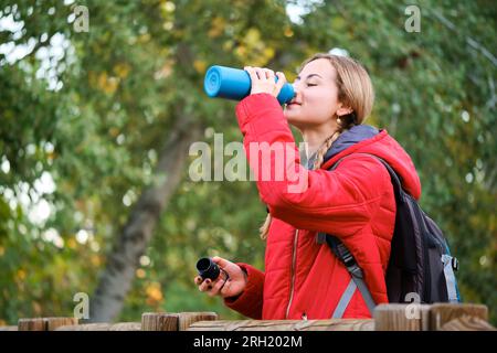 Wanderer trinken aus einer Kantine und betrachten die Aussicht auf den Wald. Stockfoto